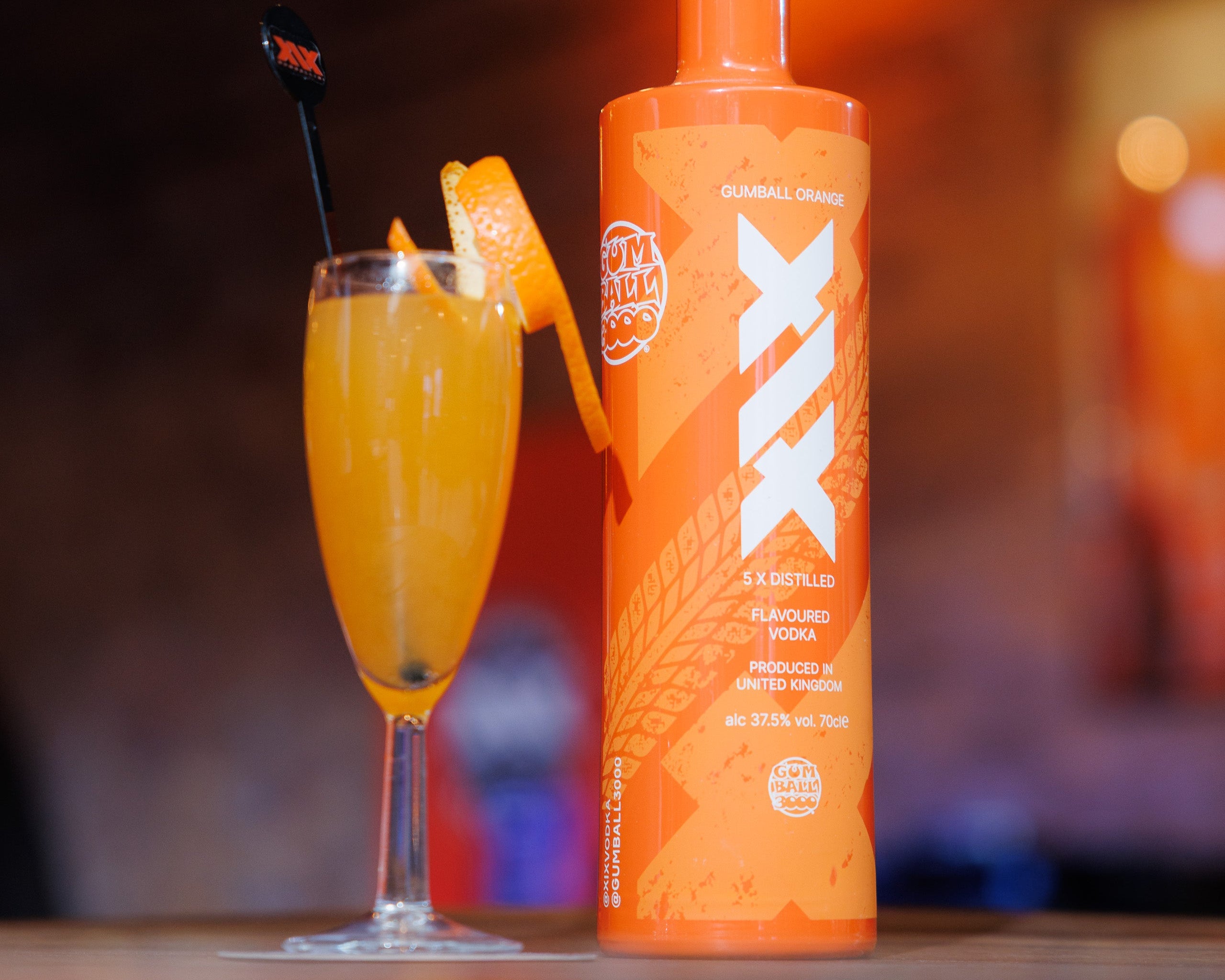 The Official Cocktail of the Gumball Rally. Peach Mimosa "Gumballini". And Orange bottle and cocktail with a blurred background
