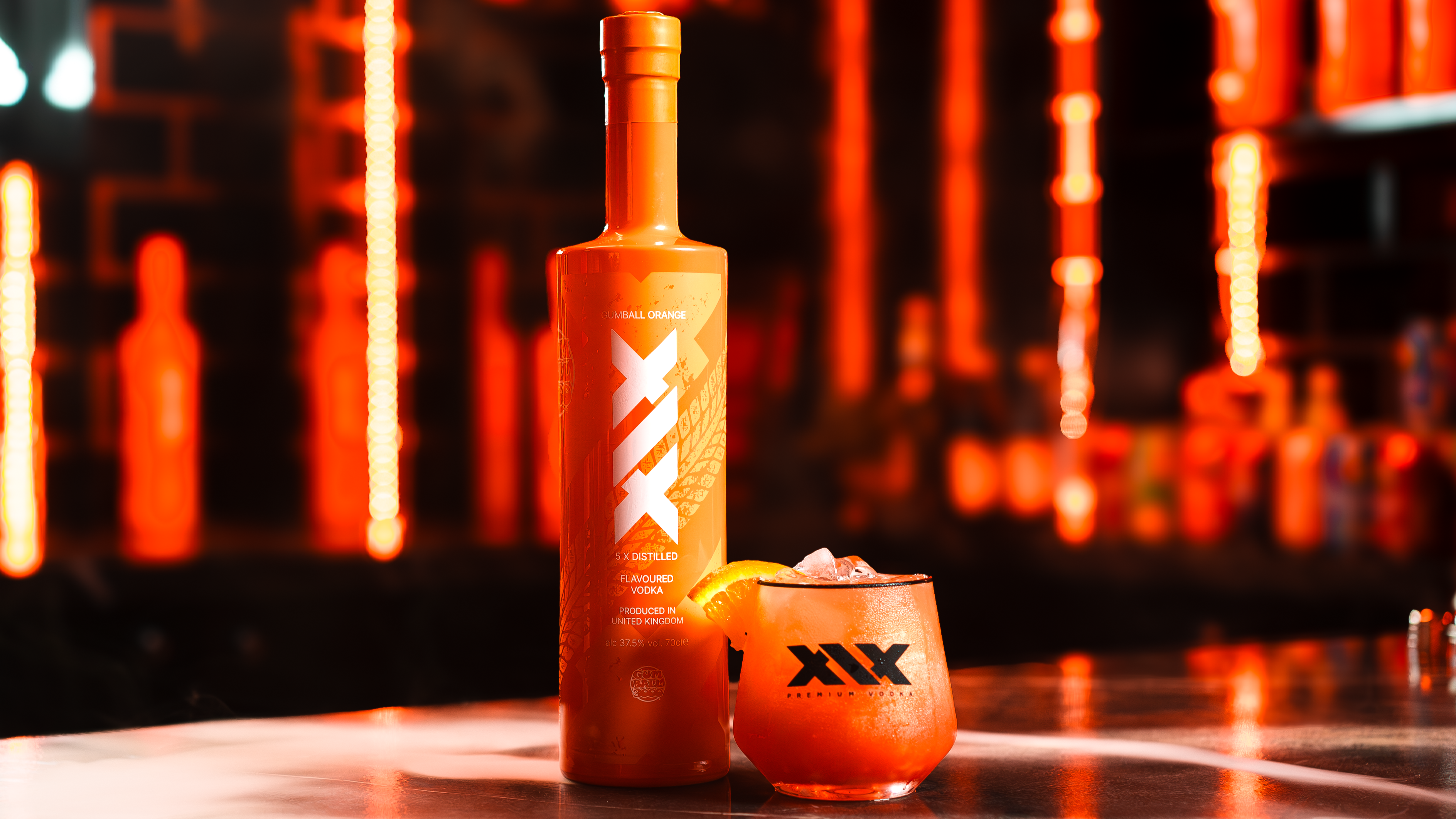 Bottle and glass of XIX cocktail on a bar with neon lights in the background