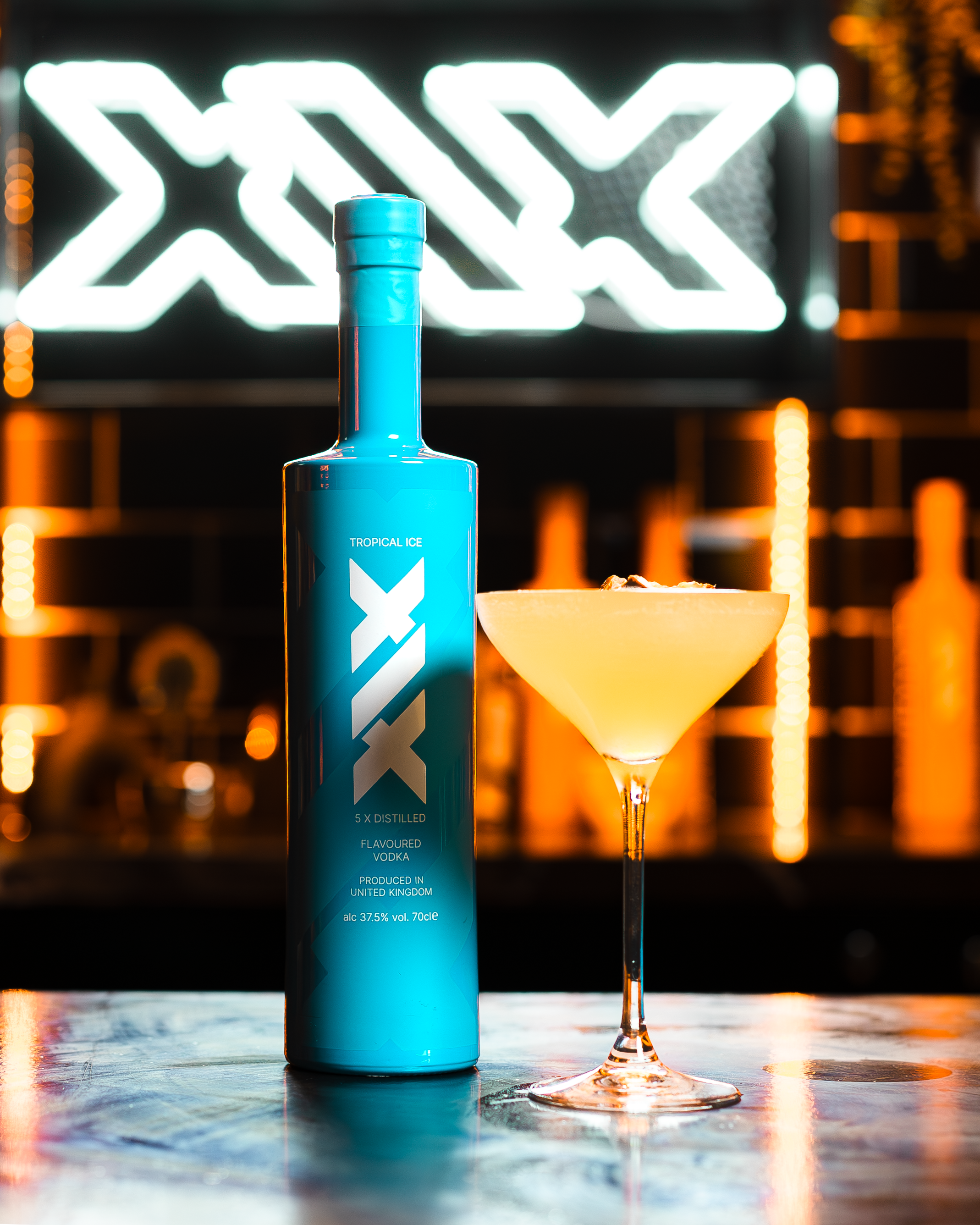 Blue bottle of XIX vodka with a cocktail in a bar setting