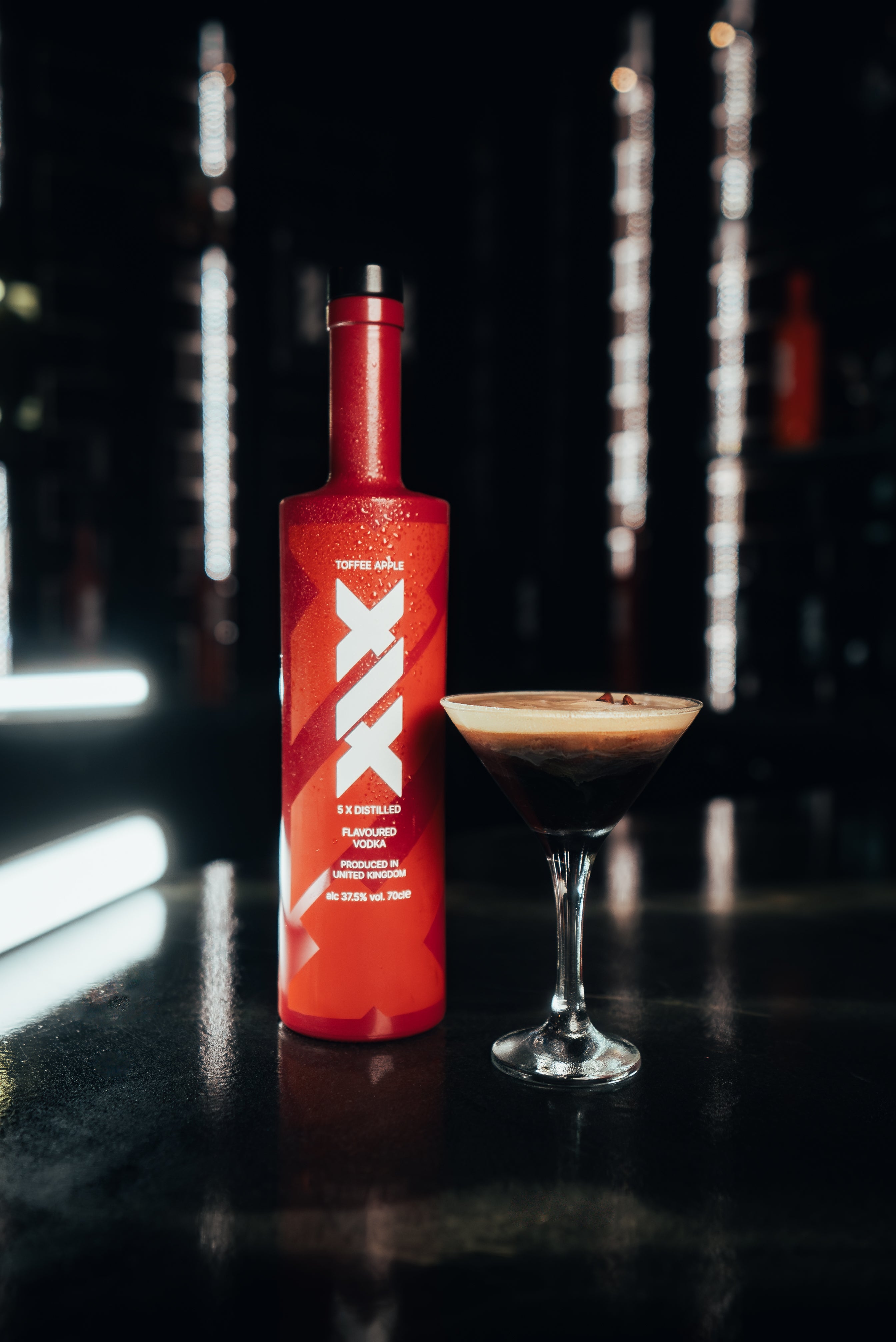 Brown bottle of XIX cocktail mixer with a martini glass on a dark background