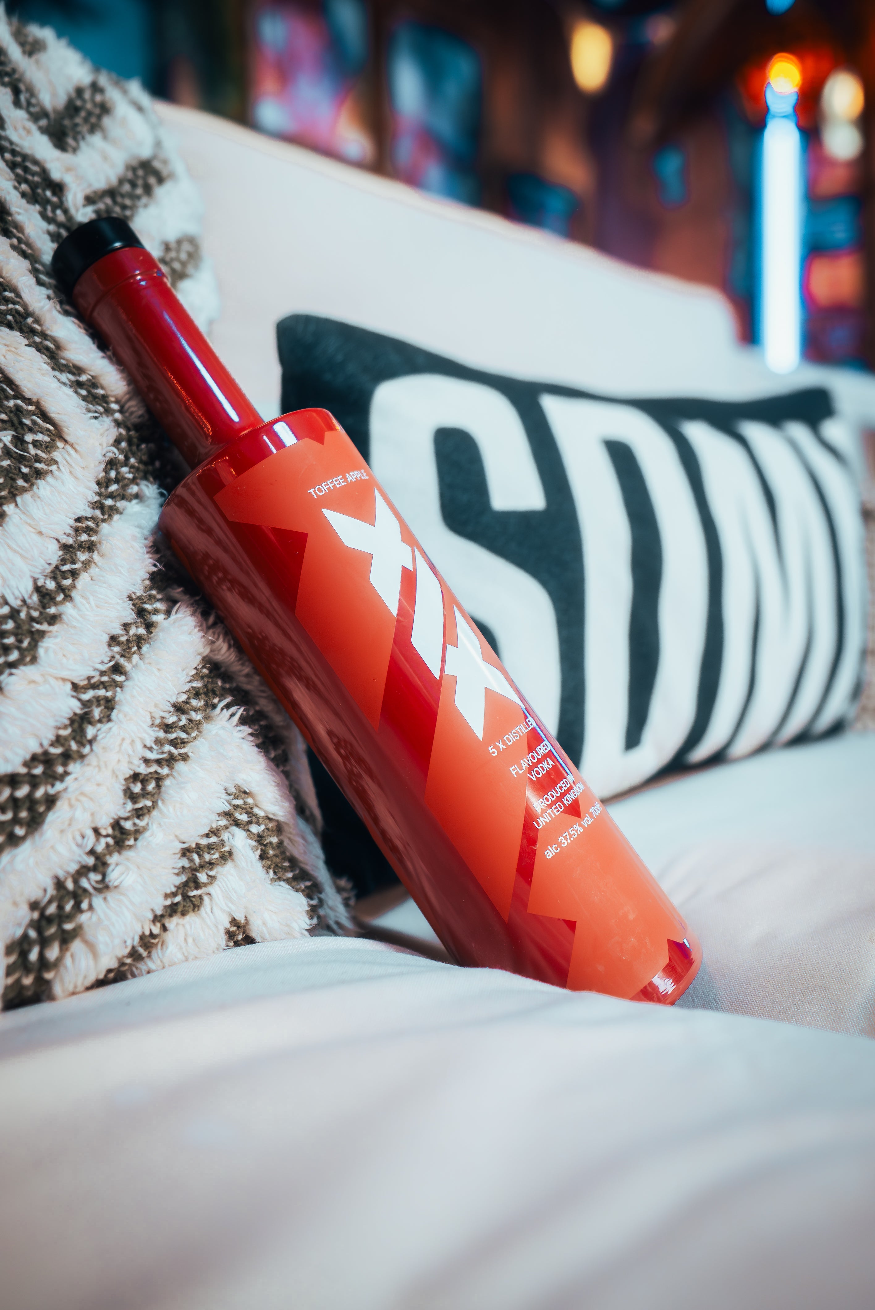 Brown and white bottle with 'Xia' branding on a couch